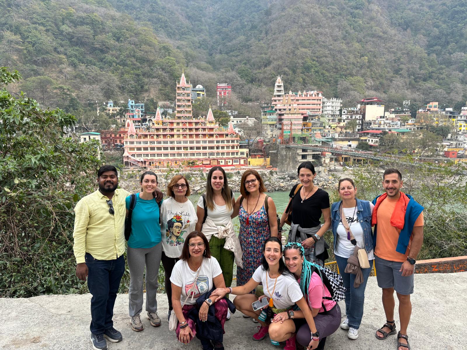 Grupo de viajeros posando frente al Templo Trayambakeshwar, rodeados de paisajes montañosos.