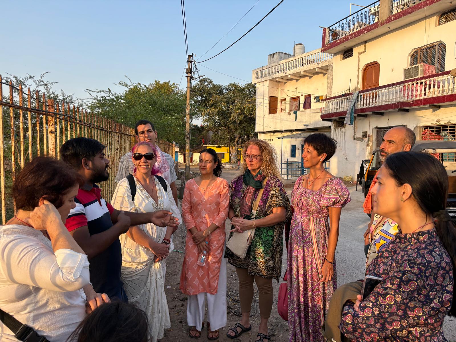 Grupo de viajeros en un tour guiado, explorando una calle en India, escuchando al guía.