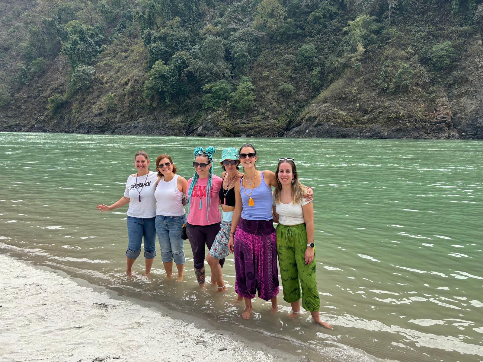 Un grupo de viajeros posando en la orilla de un río rodeado de vegetación.