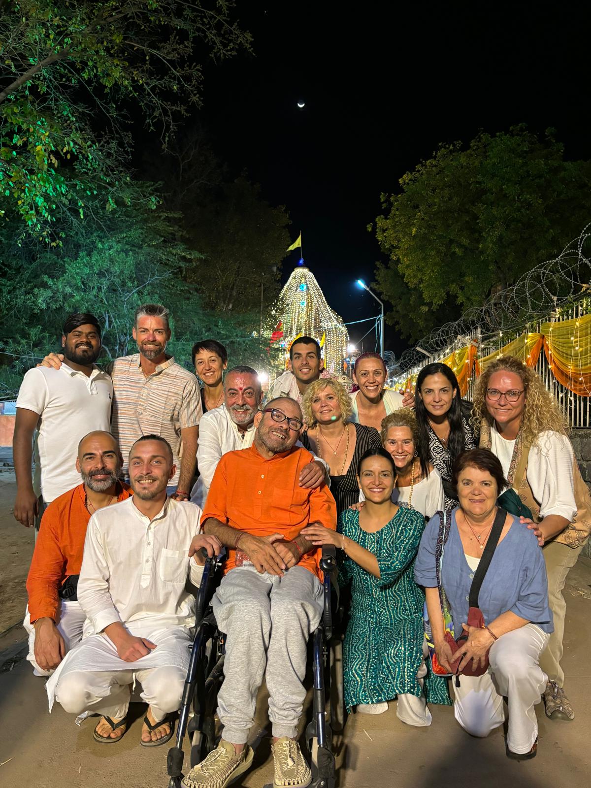 Un grupo de viajeros posa frente a un templo iluminado en India durante la noche, mostrando camaradería.