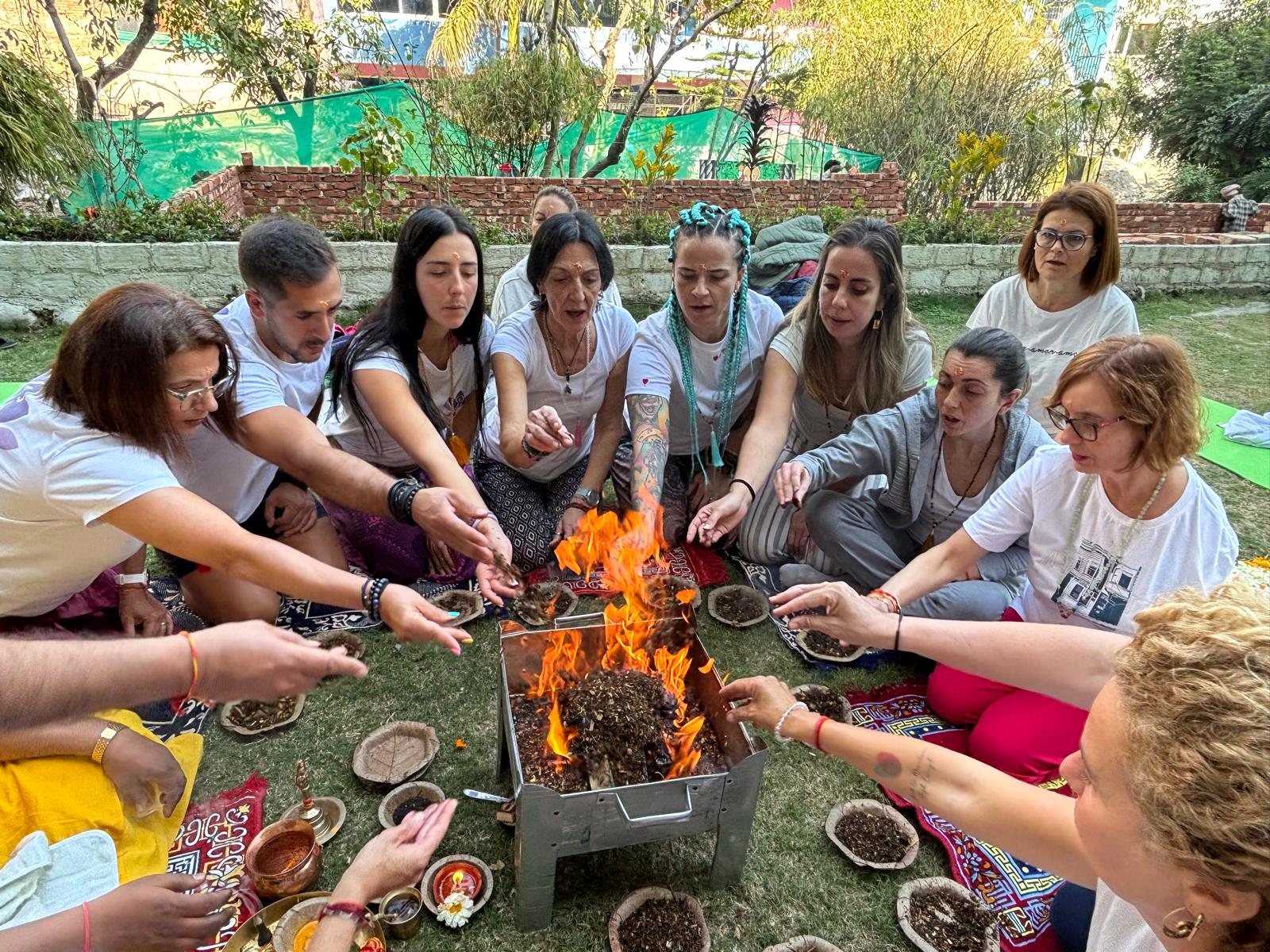 Grupo participando en una ceremonia de fuego al aire libre, rodeados de ofrendas rituales.