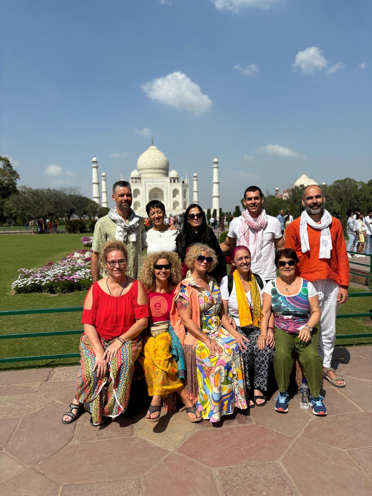 Grupo de viajeros posando frente al Taj Mahal en un día soleado.