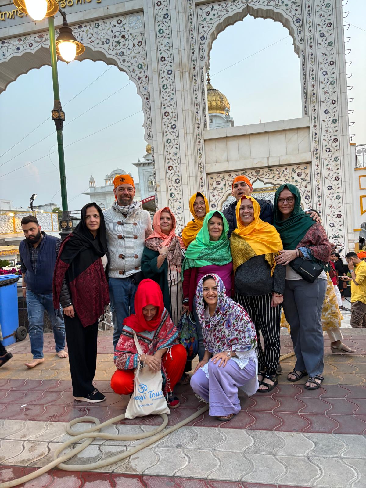 Grupo de viajeros visita un templo histórico en la India, vistiendo ropas tradicionales coloridas.