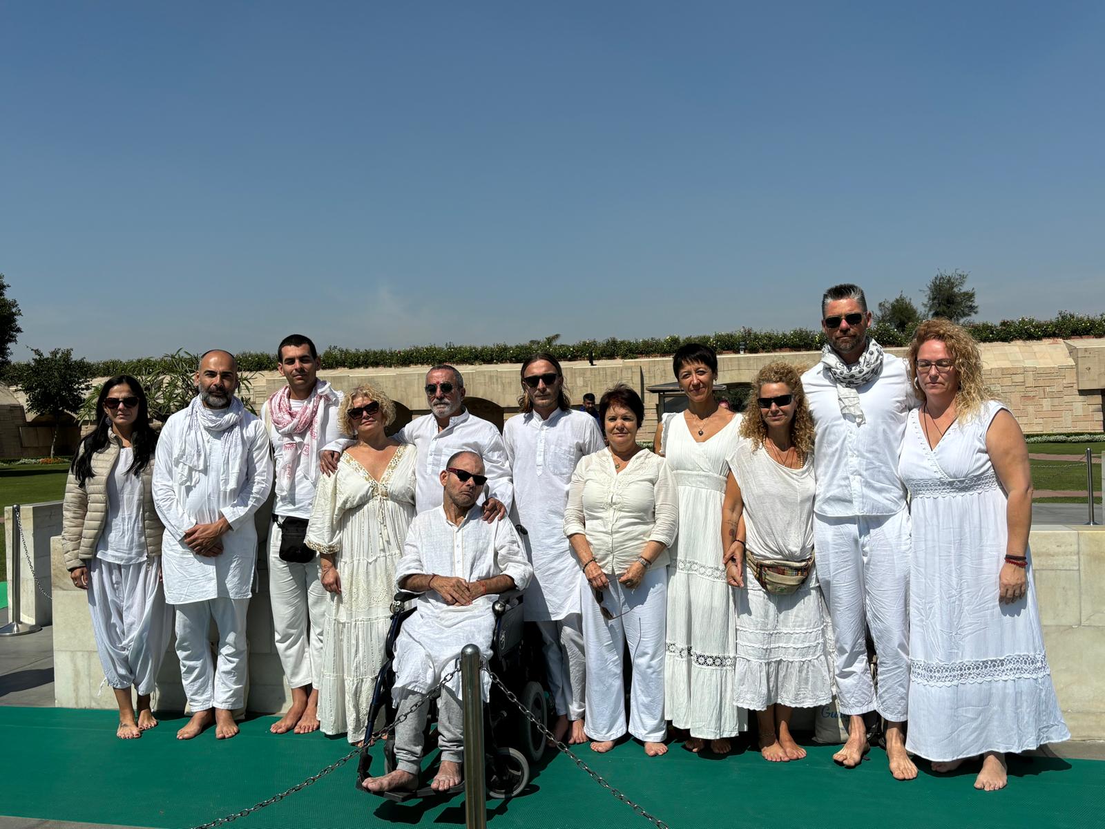 Turistas en grupo, vestidos de blanco, posan al aire libre en un sitio cultural en India.