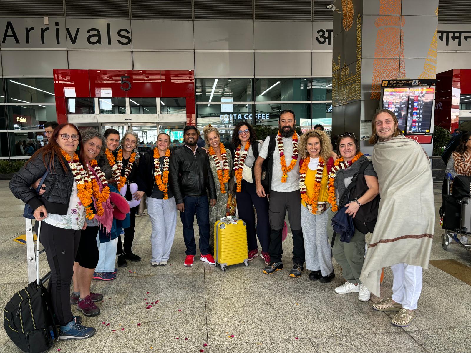 Un grupo de viajeros llega a India, usando guirnaldas de bienvenida en el aeropuerto.