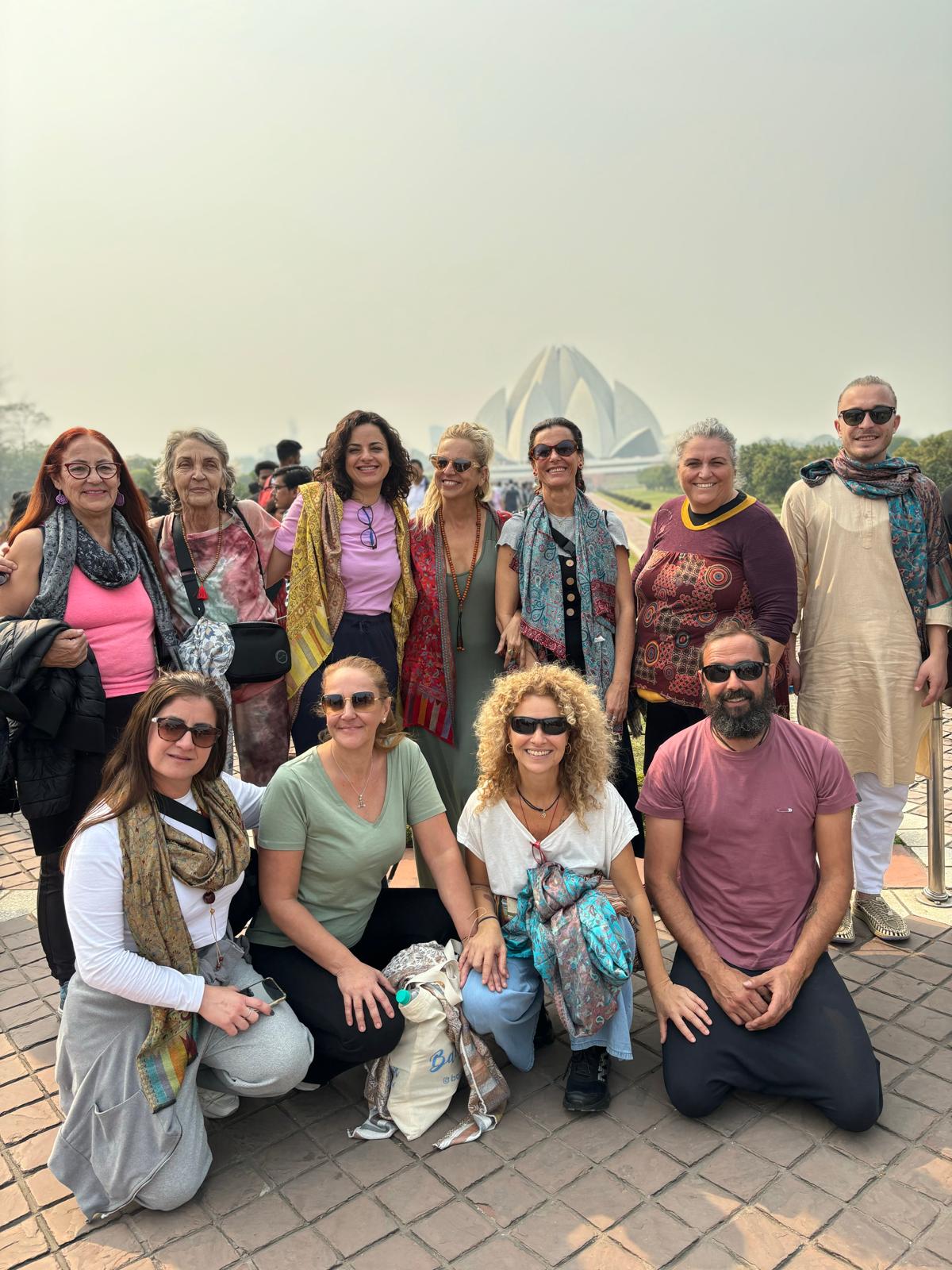 Grupo de viajeros posando frente al Templo del Loto en India en un día soleado.