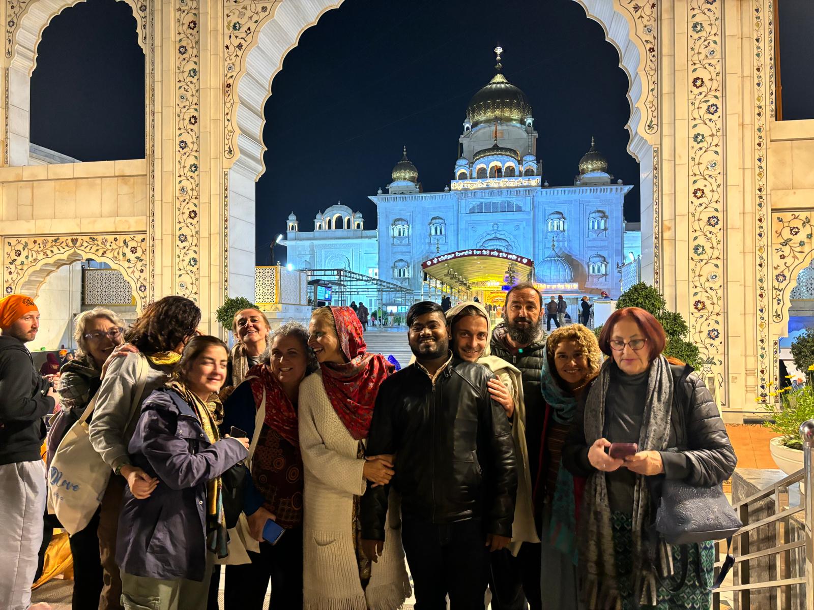 Grupo de viajeros en India disfrutando la visita nocturna a un templo iluminado.