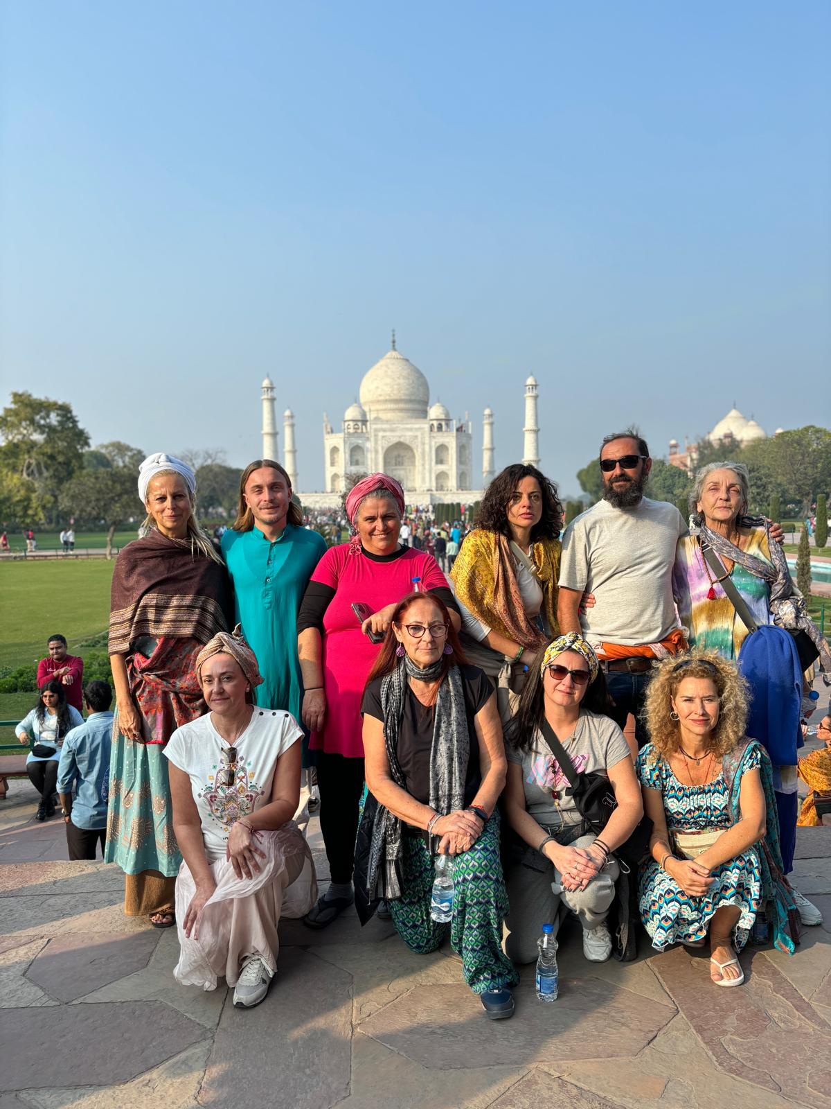 Un grupo de viajeros posando frente al Taj Mahal en un día soleado.