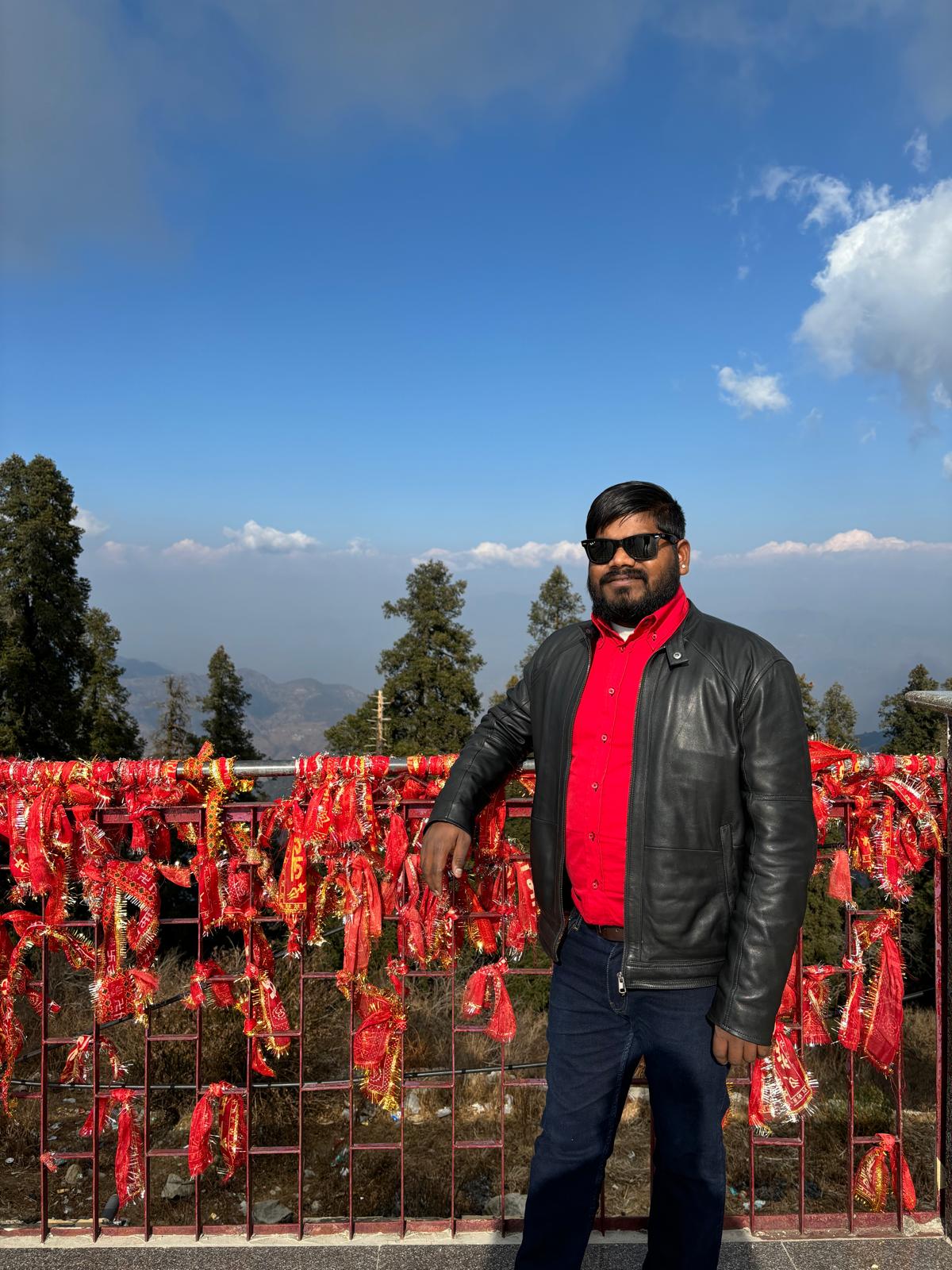 Sachin Rajak junto a un sitio ceremonial con cintas rojas de deseos, explicando tradiciones espirituales.